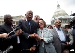 Lawmakers John Lewis and Nancy Pelosi hold hands while singing "We Shall Overcome" at the Capitol Building in Washington June 23, 2016.