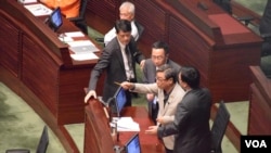 獨立議員黃毓民(持鉛筆者)拒絕保安人員將他帶離會議廳。（美國之音 湯惠芸攝）