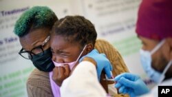 Markeata West holds her daughter, Justice, 6, as she receives the Pfizer COVID-19 vaccine for children 5-11 from Dr. Eugenio Fernandez at Asthenis Pharmacy in Providence, RI, Nov. 5, 2021.