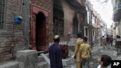 Residents look at a house of a family belonging to the Ahmadi sect, which was torched by angry mob in Gujranwala, Pakistan, July 28, 2014.