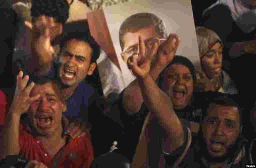 Supporters of Egypt's President Mohamed Morsi react after the Egyptian army's statement was read out on state TV, at the Raba El-Adwyia mosque square in Cairo, July 3, 2013. 