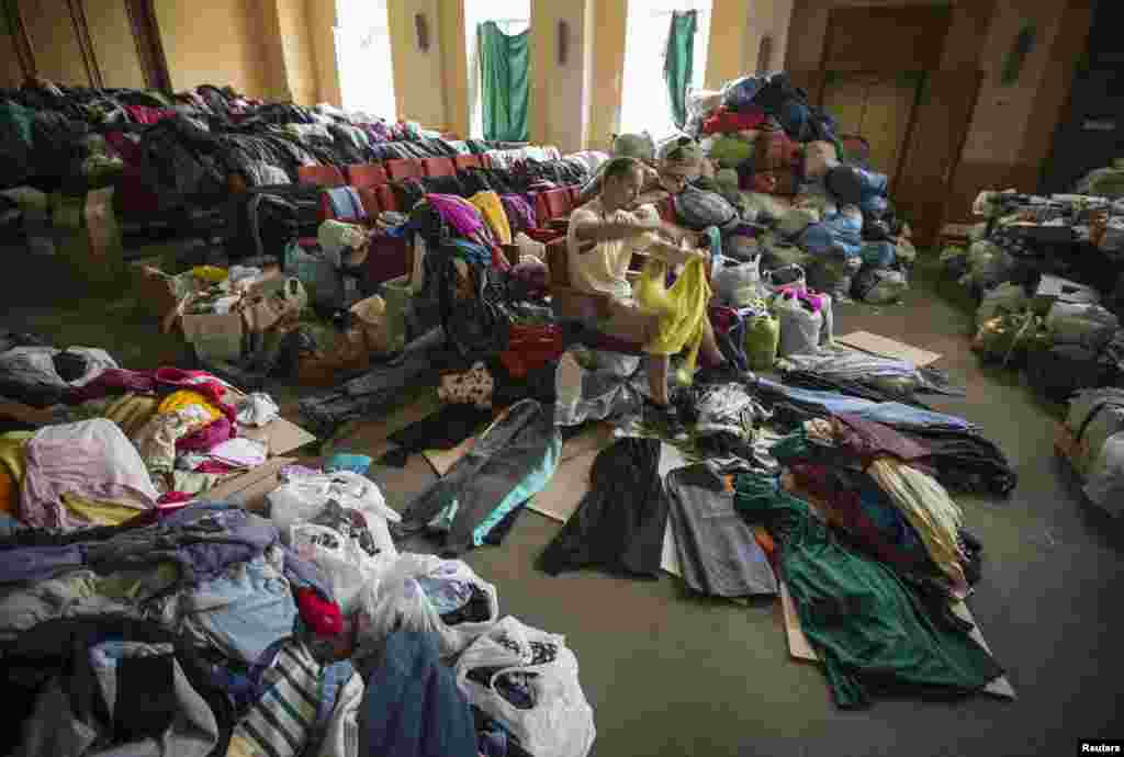 A man sorts donated clothes at a former concert hall converted into a center for collecting humanitarian aid for refugees in Donetsk, Ukraine, June 26, 2014. 