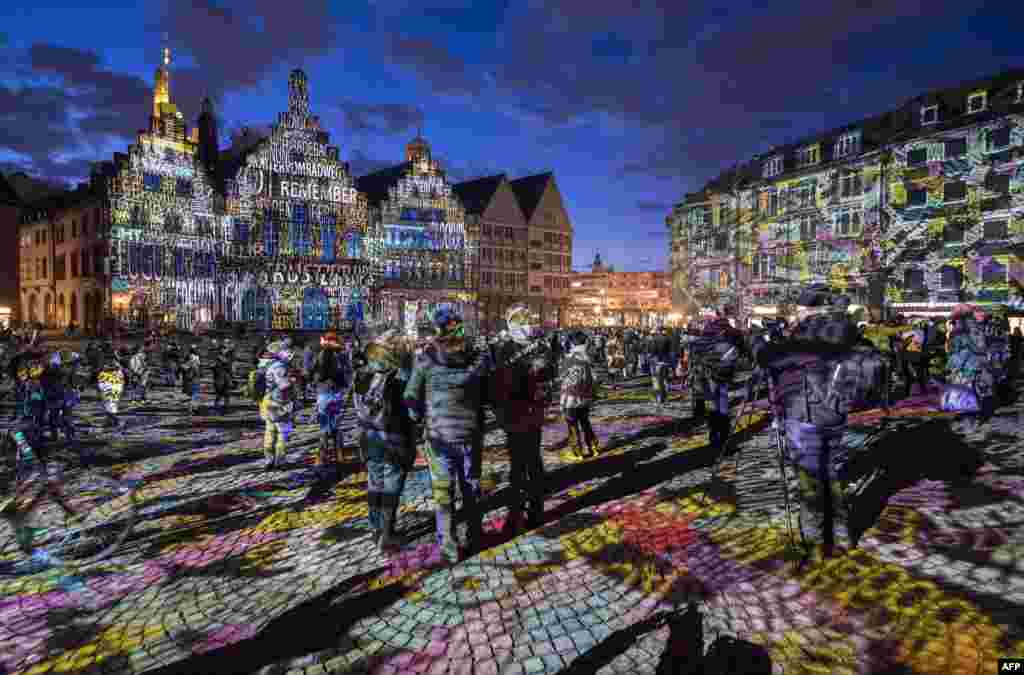 Visitors watch the light installation "Frankfurt Fades" by artist Philipp Geist, presented during the Luminale Festival of Light at Roemer square in Frankfurt, Germany, March 20, 2018.