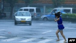 A woman walks on a street in heavy rain and strong wind in Haikou, south China's Hainan province, July 18, 2014.