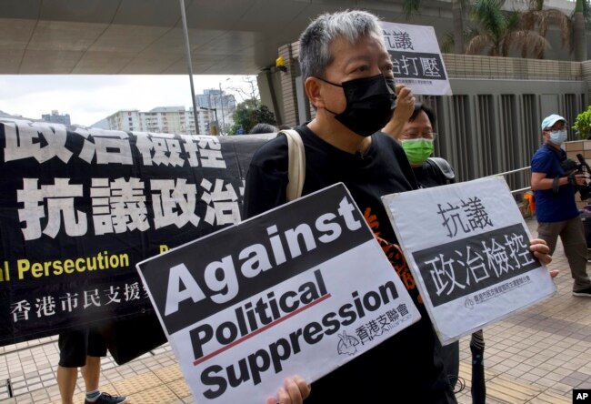 FILE - Pro-democracy activist Lee Cheuk-yan, center, holds placards as he arrives at a court in Hong Kong, April 1, 2021.
