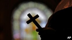 FILE - A silhouette of a crucifix is seen against the backdrop of a stained glass window inside a Catholic Church in New Orleans, Louisiana, Dec. 1, 2012.