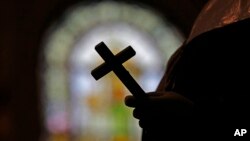 FILE - A silhouette of a crucifix is seen against the backdrop of a stained glass window inside a Catholic Church in New Orleans, Louisiana, Dec. 1, 2012.