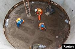 Archaeologists work on unearthed skeletons — possibly remains of Black Death victims — in the Farringdon area of London in this undated handout photo from March 2013.