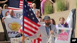 Utah County Commissioner Nathan Ivie speaks as he holds the American flag during a news conference to discuss the America's Freedom Festival's decision in Provo, Utah, June 14, 2018.