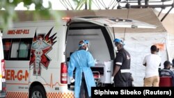 Des agents de santé discutent près d'une ambulance sur le parking de l'hôpital académique Steve Biko à Pretoria, en Afrique du Sud, le 11 janvier 2021. 