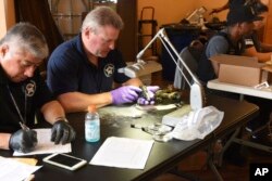 FILE - Forensic firearms examiners inspect weapons turned in by residents in a gun buy-back program in the 6th Police District, in this June 2, 2018, photo provided by the Chicago Police Department.