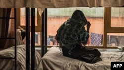 FILE - An Afghan woman looks out the window of her bedroom at a women's shelter in Kabul, March 2017.