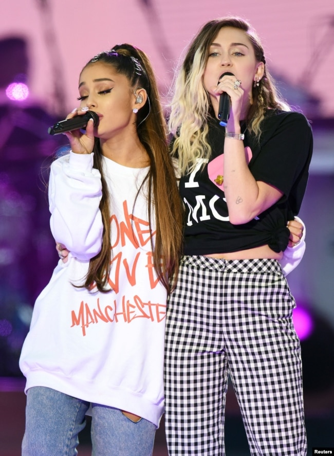 美國流行歌手愛莉安娜·格蘭德（Ariana Grande）和歌手、演員麥莉·希拉（Miley Cyrus，右）在曼徹斯特慈善音樂會上演唱（2017年6月4日）。麥莉·希拉曾經主演過美國迪斯尼公司出品的青少年電視情景喜劇《孟漢娜》
