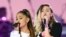 美国流行歌手爱莉安娜&middot;格兰德（Ariana Grande）和歌手、演员麦莉&middot;希拉（Miley Cyrus，右）在曼彻斯特慈善音乐会上演唱（2017年6月4日）。爱莉安娜的衣服上印着&ldquo;同一个爱&middot;曼彻斯特&rdquo;。麦莉&middot;希拉曾经主演过美国迪斯尼公司出品的青少年电视情景喜剧《孟汉娜》