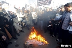 Supporters of Shi'ite cleric Moqtada al-Sadr burn fabric painted to resemble the national flags of Israel, the United Kingdom and the U.S. during a demonstration condemning the execution of Shi'ite cleric Nimr al-Nimr in Saudi Arabia, in Baghdad, Jan. 4, 2016.