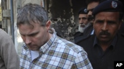 A U.S. consulate employee is escorted by police and officials out of court after facing a judge in Lahore, January 28, 2011