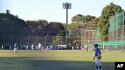Boys playing baseball adjacent to shrubbery where a high level of radioactive cesium has been detected, Edogawa, Japan, October 15, 2011.