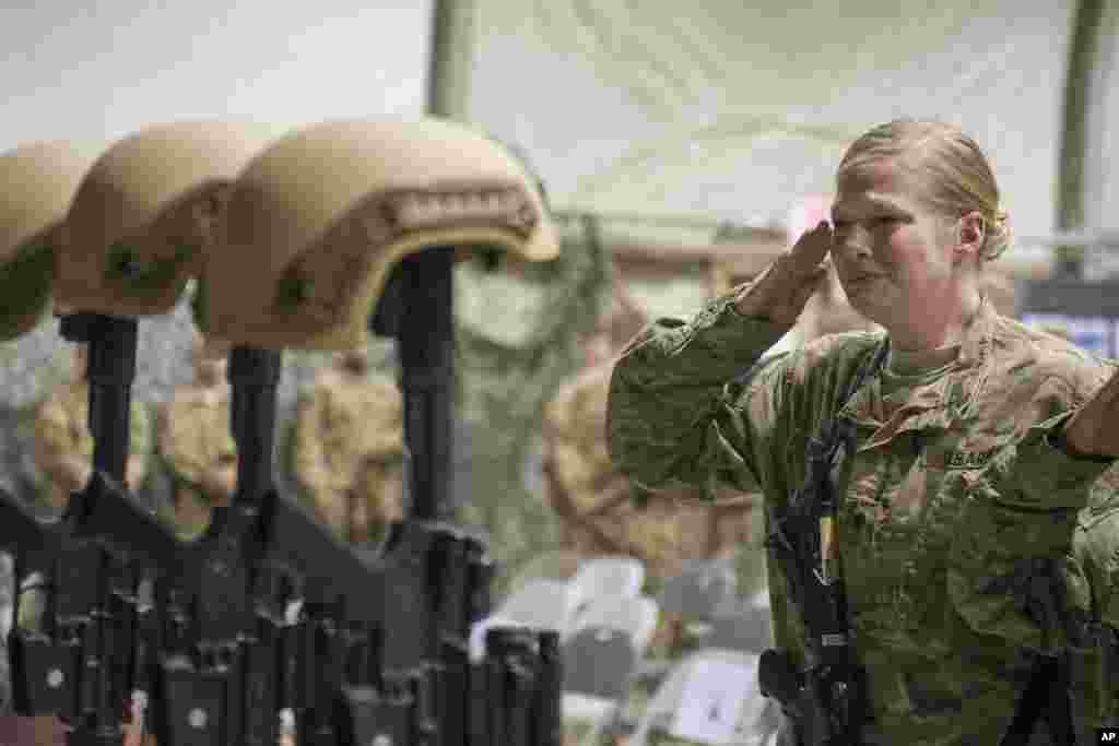 A U.S. service member salutes her fallen comrades during a memorial ceremony for six Airmen killed in a suicide attack, at Bagram Air Field, Afghanistan, Dec. 23, 2015.