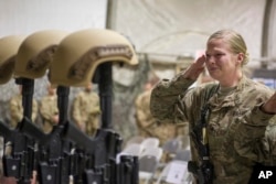 FILE - A U.S. service member salutes her fallen comrades during a memorial ceremony for six airmen killed in a suicide attack, at Bagram Air Field, Afghanistan, Dec. 23, 2015.
