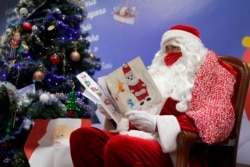 A postal worker dressed as Santa, reads letters to addressed to "Pere Noel" - Father Christmas in French - decorated with love hearts, stickers and glitter, in Libourne, southwest France, Monday, Nov. 23, 2020. (AP Photo/Francois Mori)