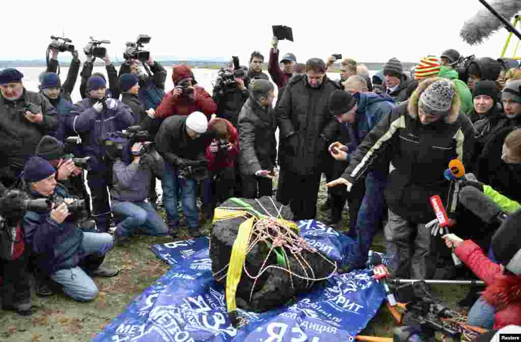 An object, which is a piece of a meteorite according to local authorities and scientists, is on display on the bank of the Chebarkul Lake, after it was lifted from the bottom of the lake, some 80 kilometers (50 miles) west of Chelyabinsk, Russia.