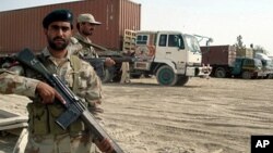 Pakistani paramilitary soldiers stand alongside trucks carrying NATO supplies at the border town of Chamam, Pakistan, September 30, 2010.