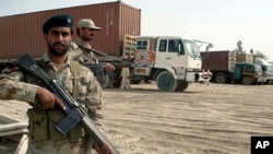 Pakistani paramilitary soldiers stand alongside trucks carrying NATO supplies at the border town of Chamam, Pakistan, 30 Sept. 2010