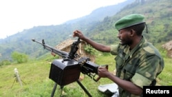 A M23 rebel fighter prepares his machine gun at their defense position in Karambi, eastern Democratic Republic of Congo (DRC) in north Kivu province, near the border with Uganda, July 12, 2012. 