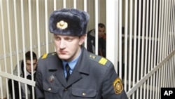 Russian citizens Artyom Breus, behind right, and Ivan Gaponov, left, sit in a cage during a court session in Minsk, Belarus, February 22, 2011 - Breus and Gaponov were detained in Minsk on December 19, 2010, during an unsanctioned rally in support of oppo