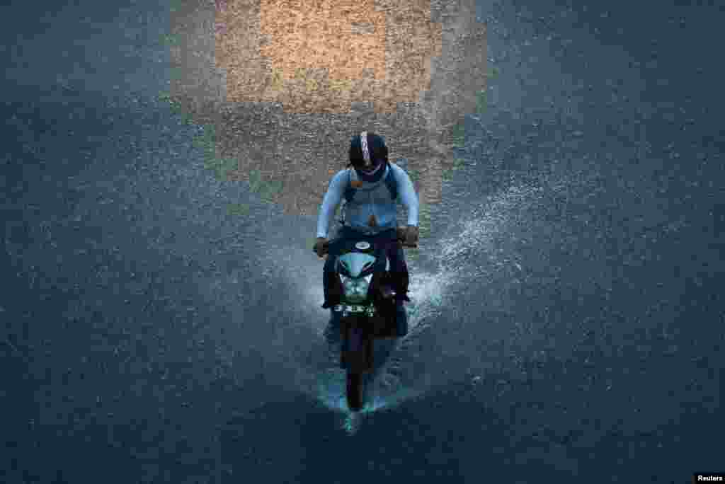 A man rides a motorbike during heavy rains in New Delhi, India.