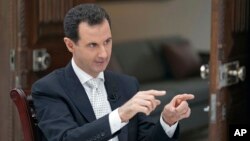 FILE - In this file photo released by the Syrian official news agency SANA, Syrian President Bashar Assad speaks during an interview with the Greek Kathimerini newspaper, in Damascus, May 10, 2018.