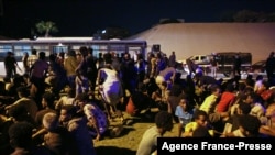 Migrants sit on the ground after being recaptured by Libyan security forces following an escape attempt from a detention facility in the capital, Tripoli, Oct. 8, 2021. Guards shot dead six migrants at the facility, the International Organization for Migration said.