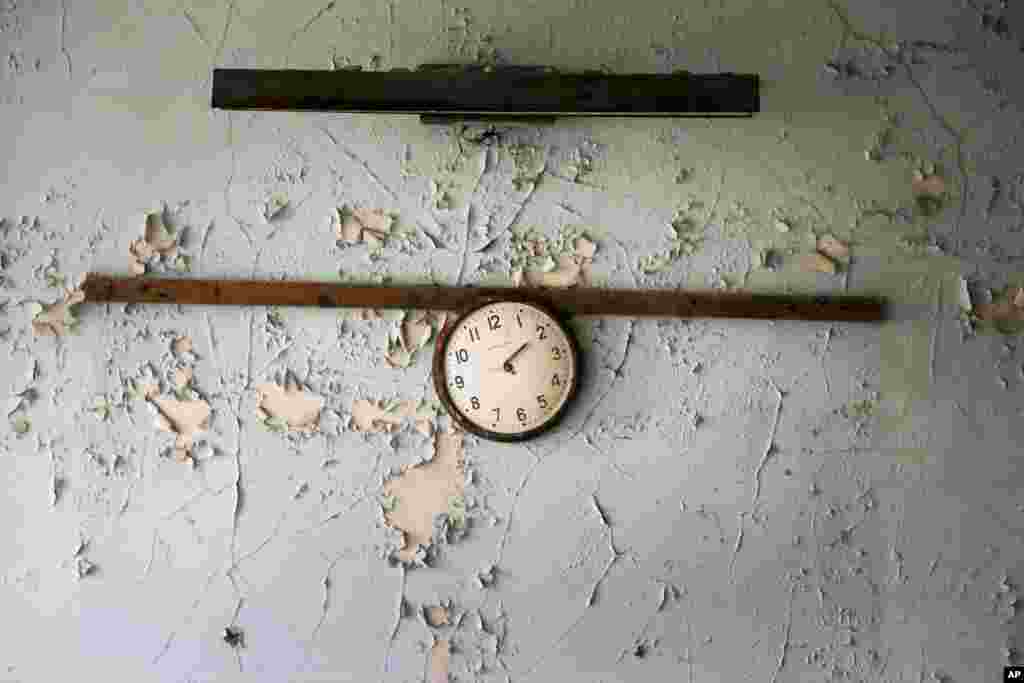 A broken clock hangs on a wall in a school in the deserted town of Pripyat, some 3 kilometers from the Chernobyl nuclear power plant Ukraine.