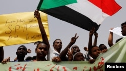 Protesters wave Sudanese flags, hold banners and chant slogans during a demonstration in front of the Defense Ministry in Khartoum, Sudan, April 18, 2019. 