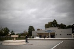 Seorang jurnalis mengenakan masker pelindung wajah sebagai tindakan pencegahan penyebaran Covid-19 selama sholat Jumat di luar masjid resmi pertama ibu kota di Athena, Yunani, 6 November 2020. (Foto: REUTERS/Alkis Konstantini)