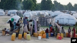 FILE- People displaced by Islamist extremists fetch water at the Muna camp in Maiduguri, Nigeria.