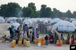 FILE - People displaced by Islamist extremists fetch water at the Muna camp in Maiduguri, Nigeria.