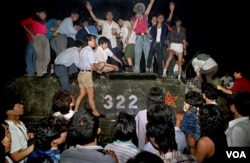 FILE - In this early June 4, 1989 photo, civilians with rocks stand on a government armored vehicle near Chang'an Boulevard in Beijing as violence escalated between pro-democracy protesters and Chinese troops,