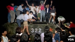 FILE - In this early June 1989, photo, civilians with rocks stand on a government armored vehicle near Chang'an Boulevard in Beijing as violence escalated between pro-democracy protesters and Chinese troops, leaving hundreds dead overnight.