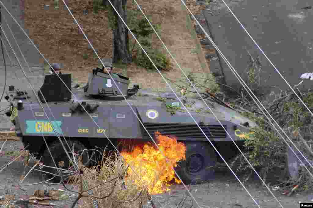 National Guards look at a fire under their armored vehicle. The fire was started after it was hit by a Molotov cocktail during a protest against Venezuelan President Nicolas Maduro's government in San Cristobal, about 660 km southwest of Caracas, Feb. 27, 2014.