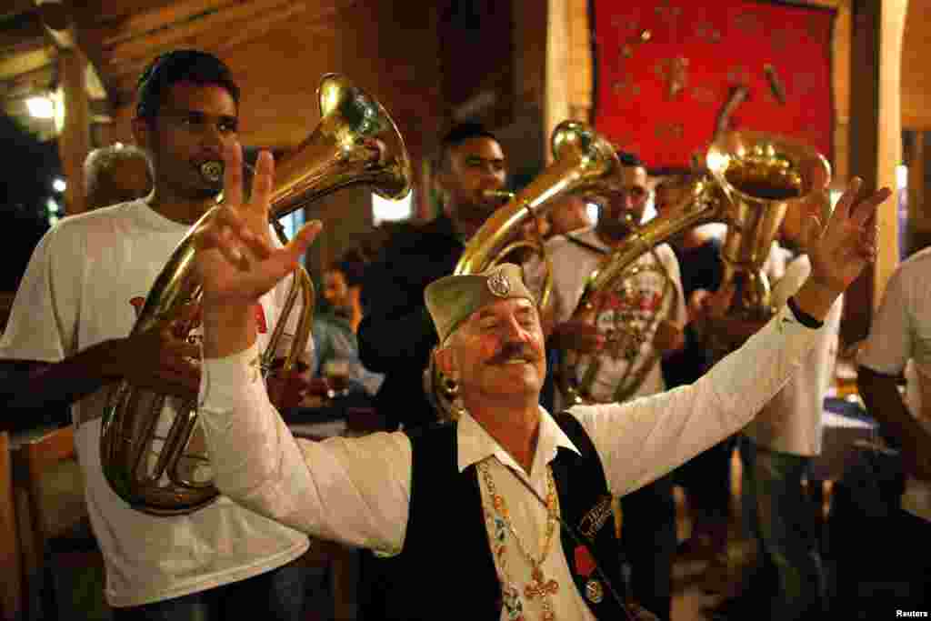 A man wearing traditional Serbian clothing is surrounded by a band during the 54th annual brass band festival in the Serbian village of Guca. Every year Guca is swamped by thousands of people taking part in the celebration of brass band music.