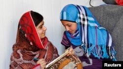 Pakistani teenage activist Malala Yousafzai (L), who was shot in the head by the Taliban for campaigning for girls' education, talks to Syrian refugee Mazoon Rakan, 16, about Mazoon's experience in the camp during her visit to the Zaatri refugee camp, in 