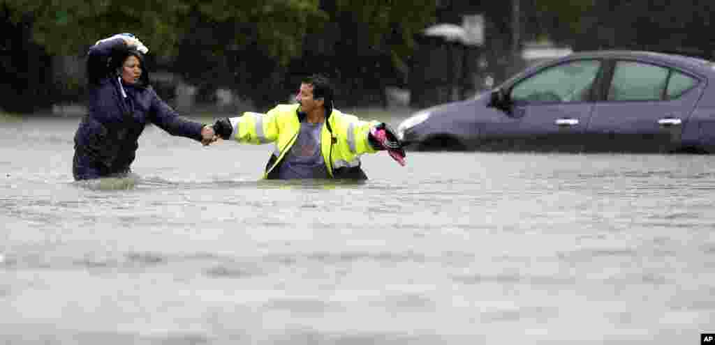 Alberto Lopez, right, helps his wife Glenda wade through floodwaters as they evacuate their flooded apartment complex in Houston, Texas. Storms have dumped more than a foot of rain in the Houston area, flooding dozens of neighborhoods and forcing the closure of city offices and the suspension of public transit.