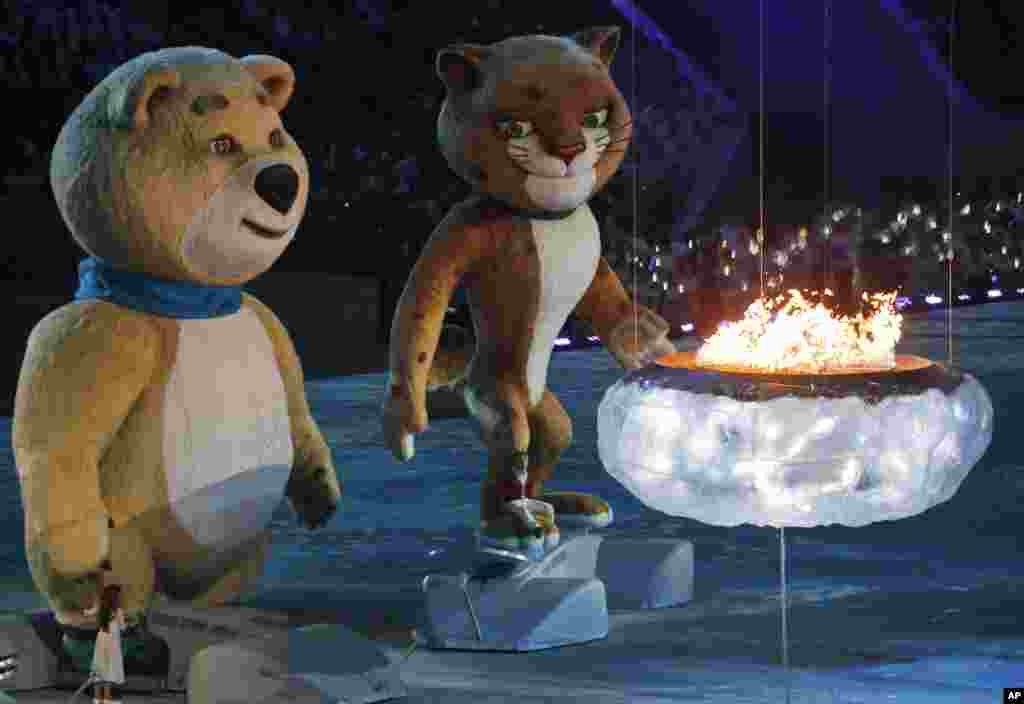 A bear and a leopard, mascots of Sochi 2014, approach a flame representing the burning Olympic cauldron, during the closing ceremony of the 2014 Winter Olympics, Feb. 23, 2014.