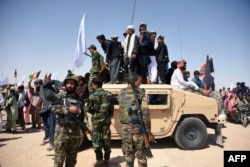 In this photo taken on June 17, 2018, Afghan Taliban militants and residents stand on a armoured Humvee vehicle of the Afghan National Army (ANA) as they celebrate a ceasefire on the third day of Eid in Maiwand district of Kandahar province.