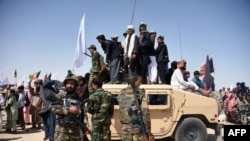 In this photo taken on June 17, 2018, Afghan Taliban militants and residents stand on a armoured Humvee vehicle of the Afghan National Army (ANA) as they celebrate a ceasefire on the third day of Eid in Maiwand district of Kandahar province.