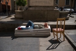 A homeless man sleeps on top of two mattresses in a street in downtown Madrid, Spain, Friday, Aug. 6, 2021. According to reports, poverty has increased considerably in the last months as Spain has been in lockdown to fight the coronavirus pandemic. (AP Photo)