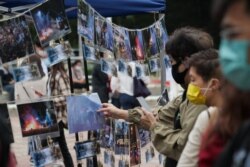 FILE - People examine pictures depicting the 2019 campus siege at the height of the city's pro-democracy protests at an exhibition in the Chinese University of Hong Kong, November 14, 2020.