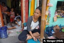 Ina Mariana sits outside a sustainable housing prototype in Kampung Tongkol, Indonesia.