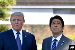 U.S. President Donald Trump, left, meets with Prime Minister Shinzo Abe upon the arrival at the Kasumigaseki Country Club in Kawagoe, near Tokyo, Nov. 5, 2017.